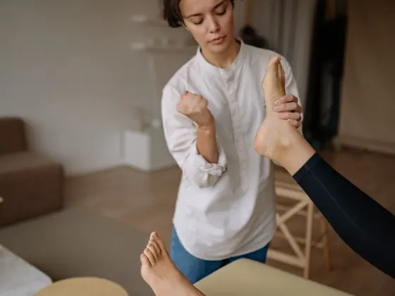 Mãos da fisioterapeuta apoiando o cotovelo de uma paciente durante avaliação da dor.