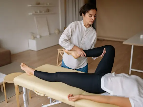 Fisioterapeuta realizando mobilização de joelho em uma paciente deitada na maca.